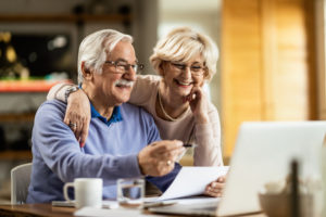 Happy mature couple using laptop while planning their home budget.